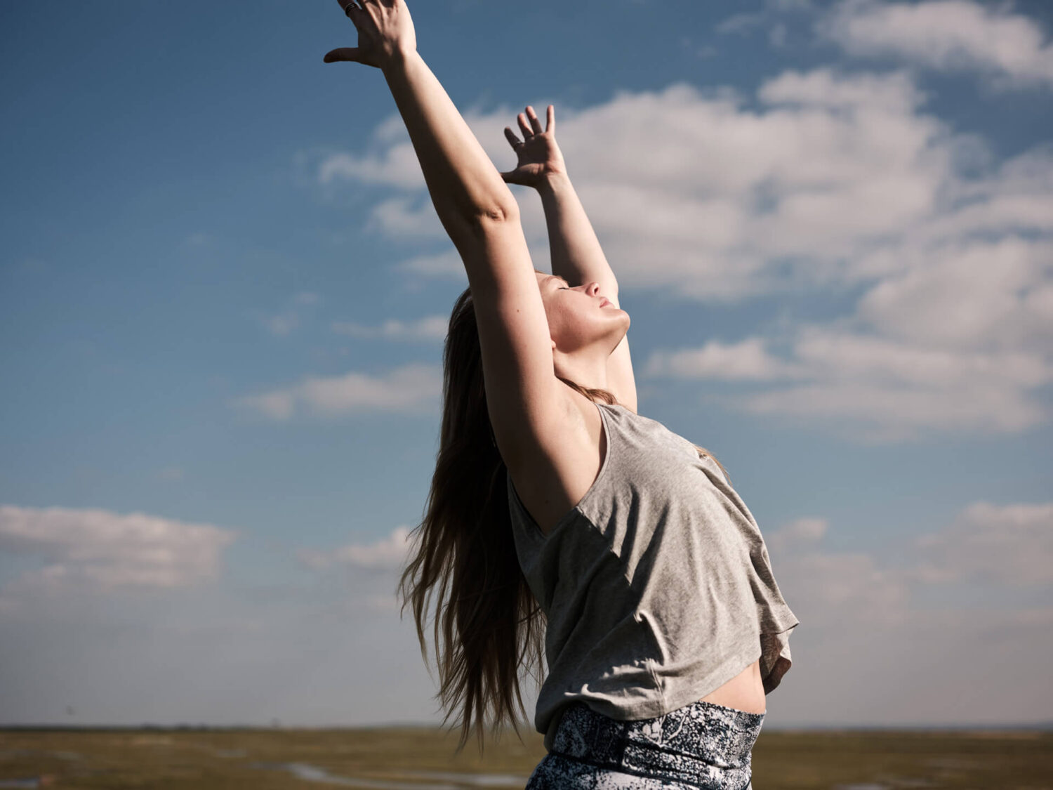 Yoga Teacher, Georgie Davies, reaches towards the blue sky. Practice yoga in Oxfordshire and online