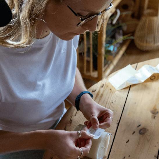 Hannah sticks a label on a Sage and Grace candle