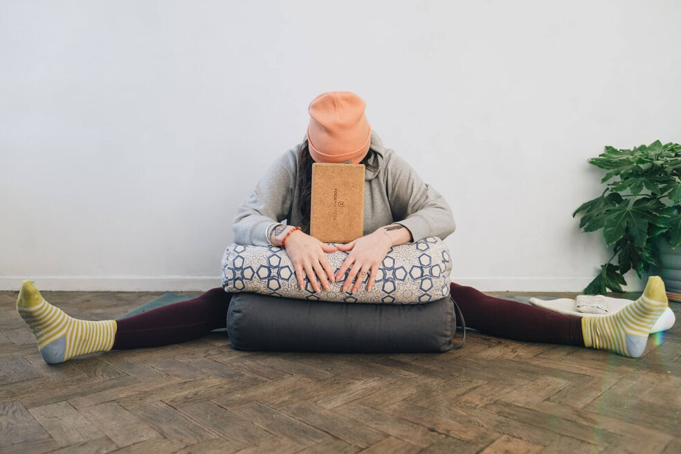 Harriet McAtee rests in a wide leg forward fold with a yoga bolster