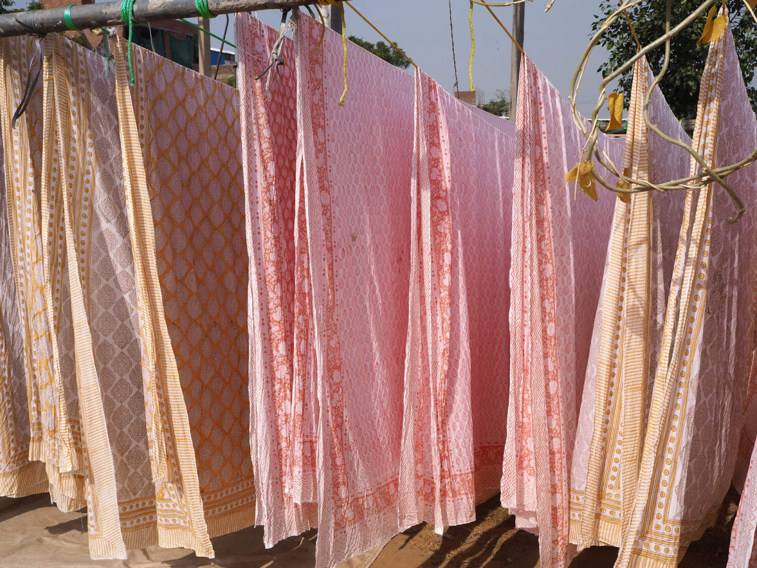 Block printed fabric hangs in the sunshine to dry