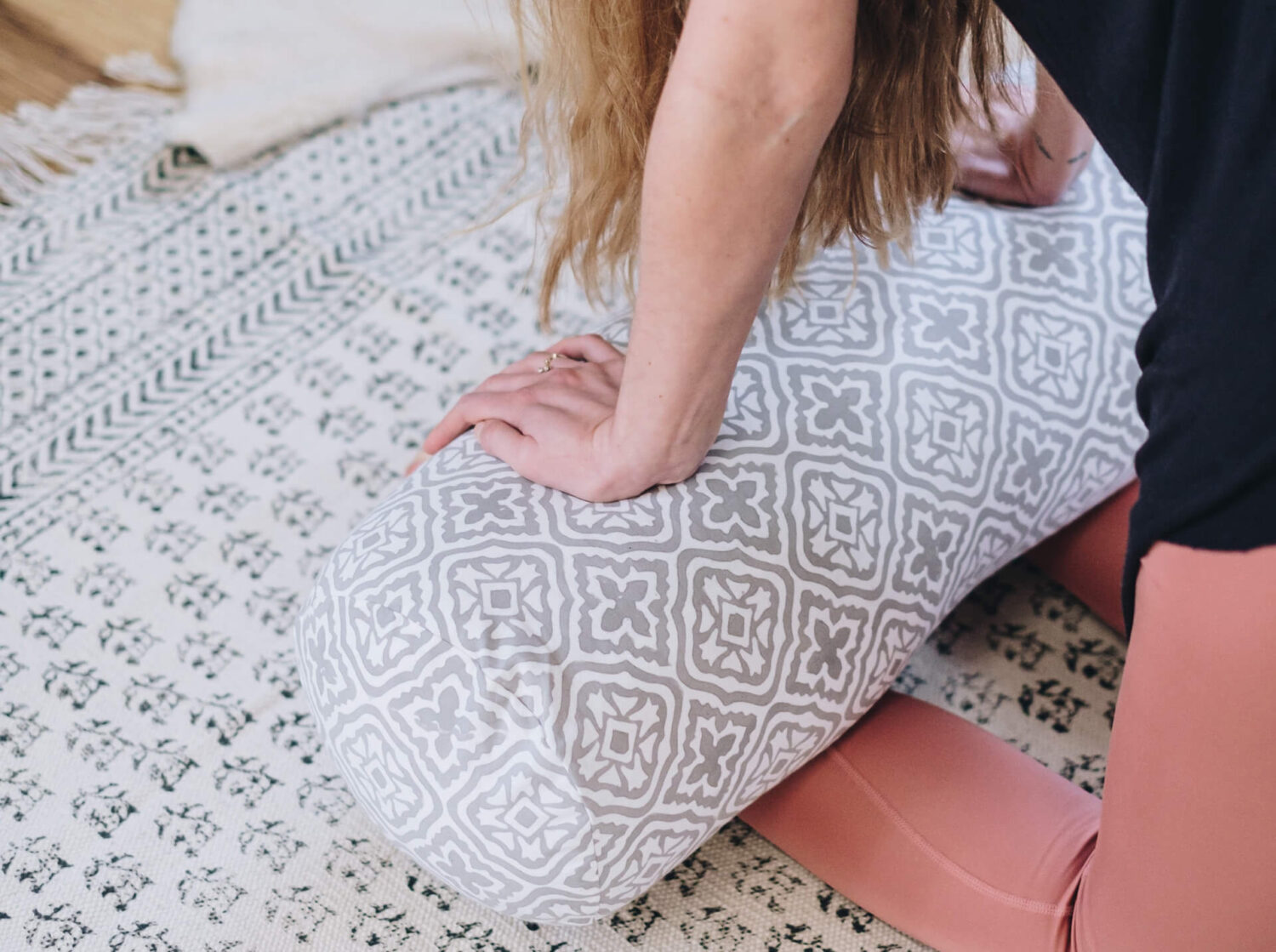 Ellie leans back onto a Yogipod tiled lattice grey bolster in camel pose